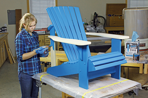 Applying blue paint to Adirondack chair