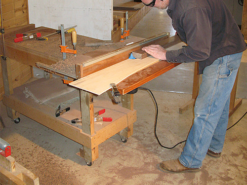 Routing walnut bookcase panel clamped to the table