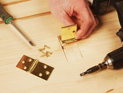 Screwing drop leaf hinges into place on table and leaf