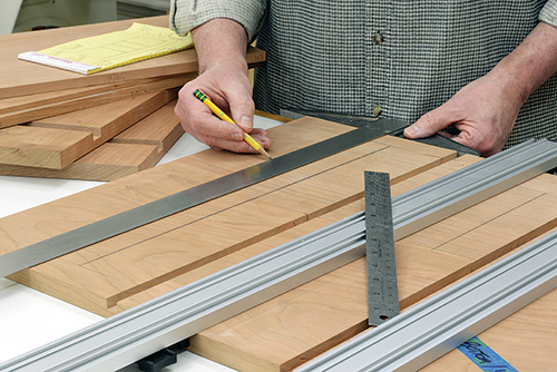 Clamp up component pairs with inside faces upward, then pencil in guidelines for routing dadoes for the dividers. A T-square ensures accuracy.