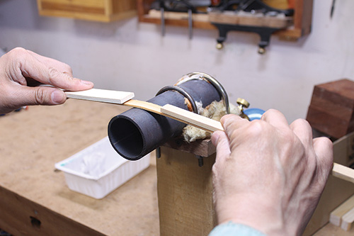 Bending thin strip of wood across hot pipe