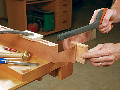 Using hand saw to trim garden bench rail cheeks