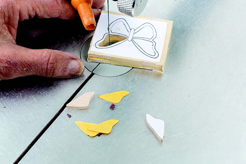 For better control, sandwich veneer for the wing decorations between thin pieces of scrap wood. Cut extra decorations to allow for breakage.