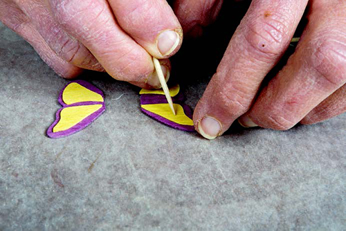 A toothpick helps position the veneer when gluing the fidgety decorations to the butterfly wings.