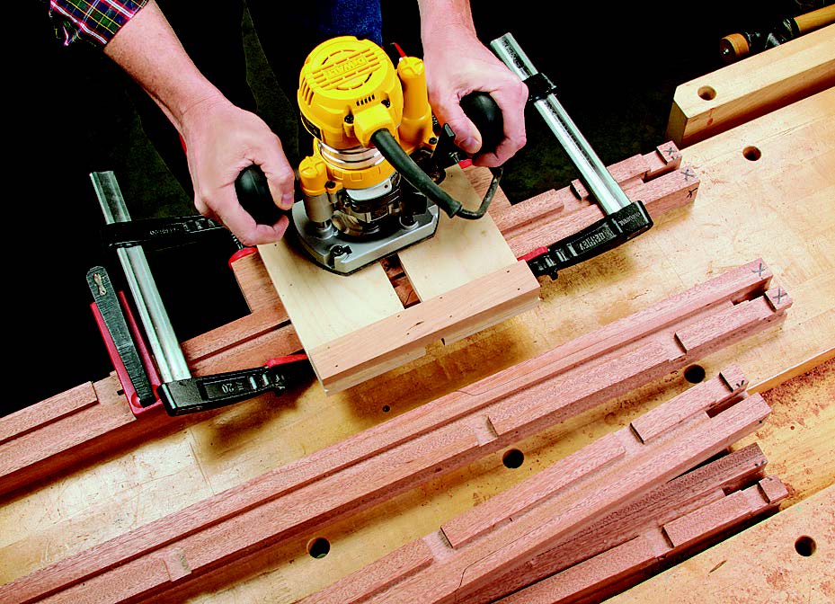 A clamped routing jig with a 3/4"-wide slot makes it easy to mill dadoes for the web frames in the legs.
