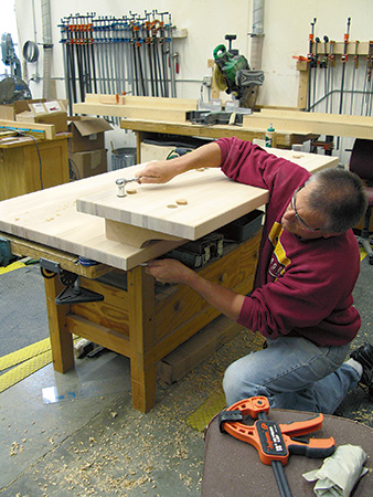 Using a wrench to attach bolts to kitchen island countertop