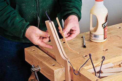 A strip of wood glued into a groove cut into the top curved edge of one leg conceals a wire that provides power for the LED lighting.