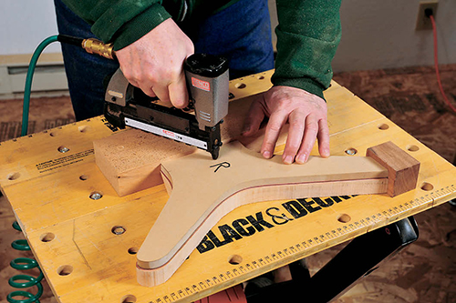 A pneumatic pin gun securely fixes the leg template to a rough-cut blank.