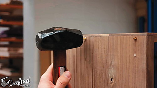 Hammering and gluing pins into place in Mid-century Modern Dresser