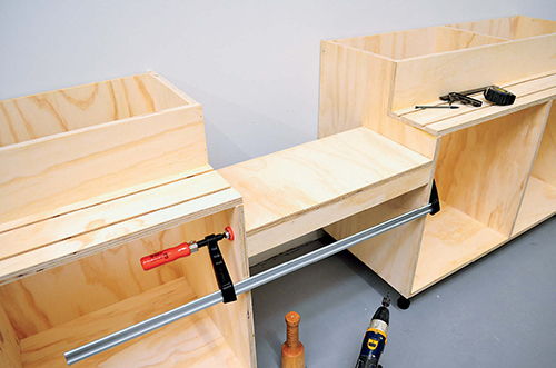 The shelf supporting the miter saw should be clamped in place and adjusted before you screw it to the cabinets.