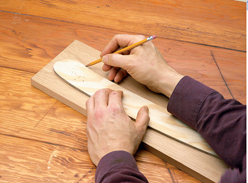 Tracing portable outdoor chair part template onto stock with pencil
