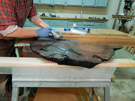 Brushing epoxy into redwood slab cracks
