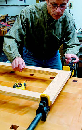 Clamp the frames with even pressure applied on the center of the joints. Check for square by measuring diagonally across the frame from corner to corner with a tape measure.