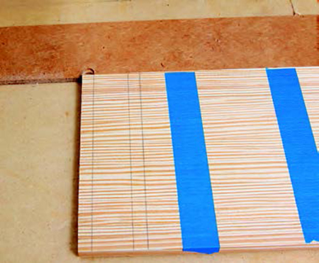 Place the strips against the hardboard fence and align the marked joint with the cutout in the fence from a previous router pass. (The router carriage has been removed for photo clarity. Also, note the self-adhesive abrasive strips on the bottom of the router carriage that prevent the workpieces from slipping. Use sandpaper to make your own.)