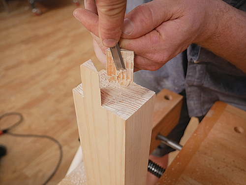 Finishing up table leg joint with chisel