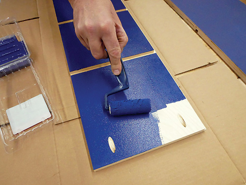 Rolling blue latex paint over bookcase parts