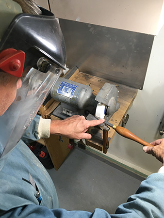 Adjusting scraper on sharpening stone