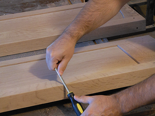 Pressing down on screwdriver to smooth sharp edge