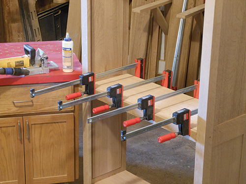 Clamping upper bookcase shelf in place