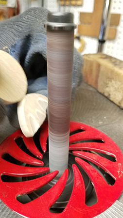 Sanding wrapper portion of candy ornament with spindle sander