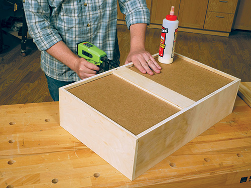 Nailing wall cabinet drawer bottom in place with a nail gun