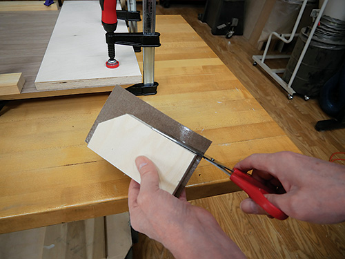 Cutting excess veneer away from plywood panel
